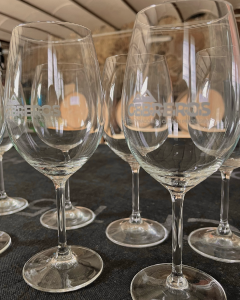 Copas de vino colocadas frente a barricas de roble en la bodega Alma Rural, simbolizando el proceso de crianza tradicional y el momento de disfrute del vino en su máxima expresión.